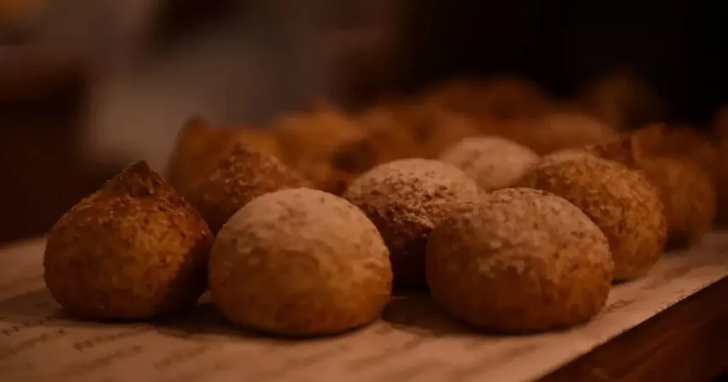 bolinho de arroz na Aquela casquinha dourada que estala nos dentes e o interior macio - o lanche perfeito para quem quer saborear sem peso na consciência. Quem disse que comida sem glúten tem que ser sem graça? Esses bolinhos de arroz feitos na airfryer vão te surpreender: crocantes por fora, cremosos por dentro e com aquele toque especial que só um tempero na medida certa pode dar. O melhor? Tudo pronto em menos de 20 minutos, sem sujar panela e usando apenas ingredientes que você provavelmente já tem na geladeira. Ingredientes para 15 unidades Base dos bolinhos 2 xícaras de arroz cozido (de preferência um dia antes) 1 ovo grande 3 colheres (sopa) de queijo parmesão ralado 2 colheres (sopa) de farinha de arroz 1 colher (sopa) de cebolinha picada Temperos essenciais 1 dente de alho amassado Sal e pimenta-do-reino a gosto 1 pitada de páprica defumada Para empanar (opcional) ½ xícara de farinha de rosca sem glúten Modo de fazer Preparo da massa Amasse bem o arroz com um garfo Misture todos os ingredientes até obter uma massa homogênea Ajuste os temperos se necessário Modelagem e cozimento Molde bolinhas com as mãos umedecidas Passe na farinha de rosca (se desejar mais crocância) Coloque na cesta da airfryer sem untar Asse a 180°C por 12-15 minutos, virando na metade do tempo Rendimento: 15 bolinhos Tempo total: 20 minutos Dificuldade: Fácil 3 segredos do sucesso Arroz um dia depois gruda melhor que o recém-cozido Parmesão ajuda a dar liga sem precisar de farinha de trigo Virar na metade garante douramento uniforme Dica matadora: Sirva com um molho rápido de iogurte natural, limão e hortelã - combina perfeitamente e deixa tudo ainda mais especial. Esses bolinhos são a prova de que dá para comer bem sem complicação. Crocantes, leves e cheios de personalidade, eles são perfeitos para o lanche da tarde, uma entrada diferente ou até como acompanhamento especial. E o melhor: ninguém vai acreditar que são sem glúten e feitos na airfryer sem glúten