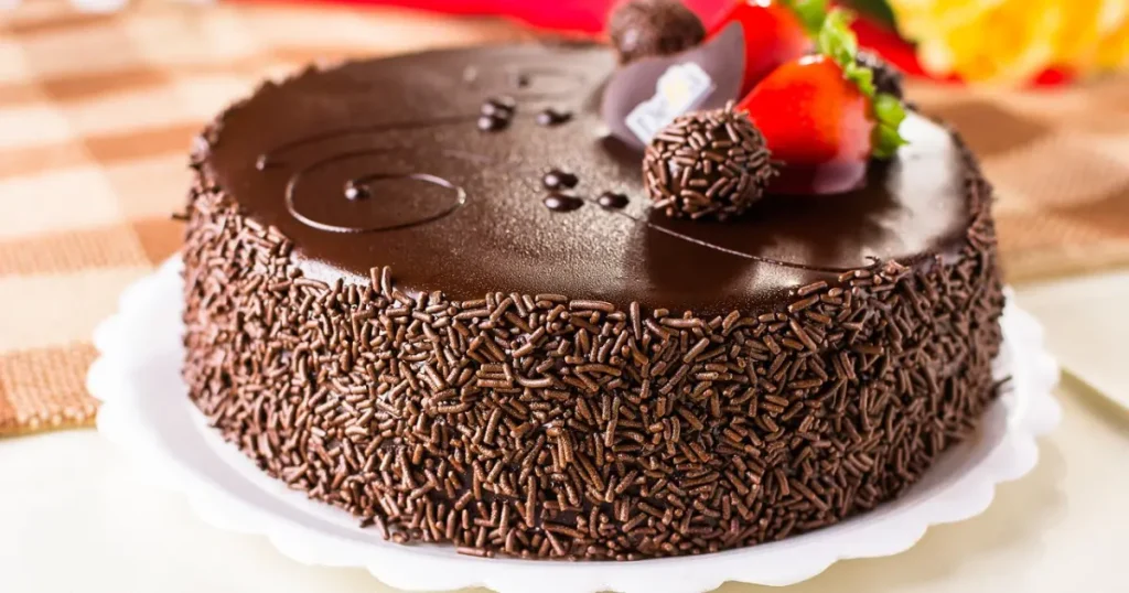 Bolo brigadeiro com chocolate granulado nas bordas e morangos enfeitando por cima