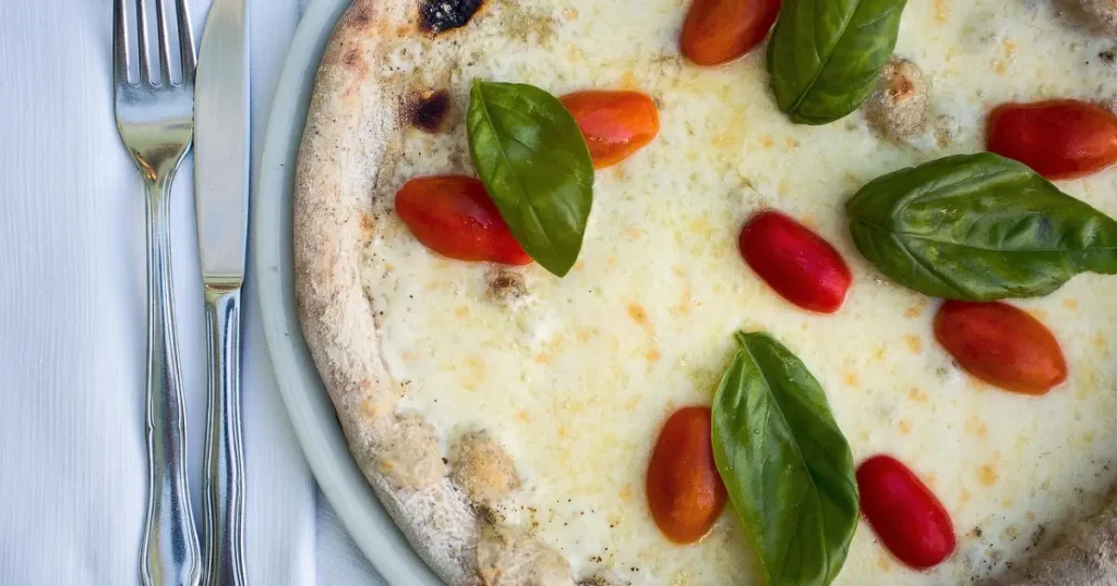 pizza branca com tomates cereja enfeitando por cima
