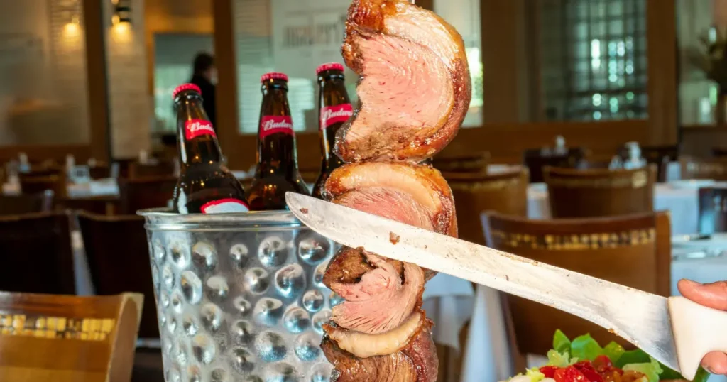 homem assando picanha na churrasqueira e mostrando o ponto certo